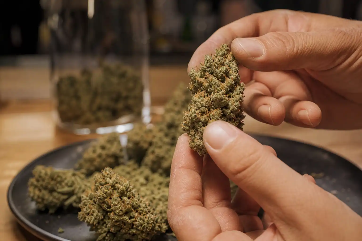 Des mains examinent un objet, autour de fleur cbd indoor, dans une cuisine.